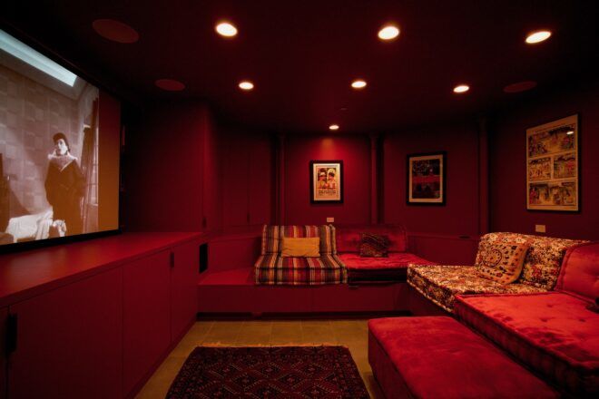 A home theatre set-up with a large window and red décor all around