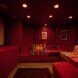 A home theatre set-up with a large window and red décor all around