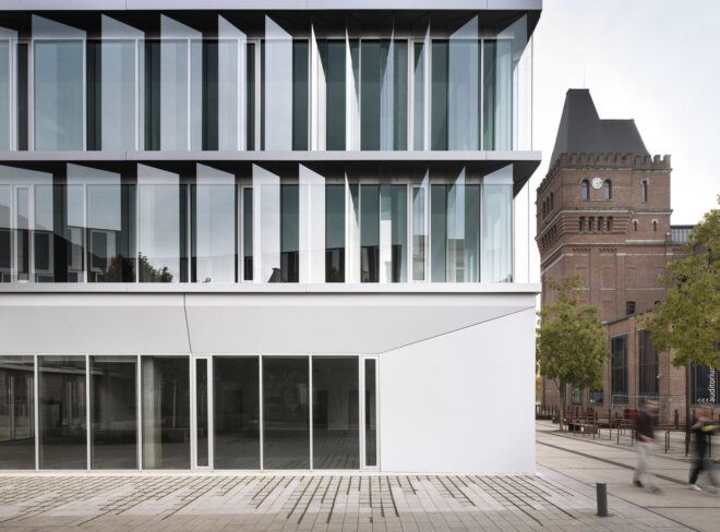 The exterior of a building with reflective, moveable shield-like structures.