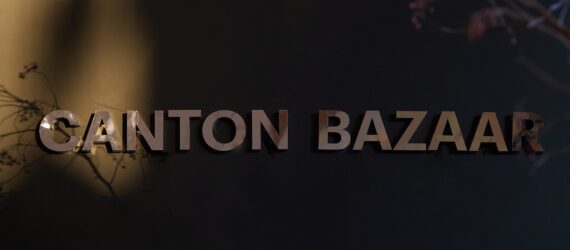 A dark background with the word Canton Bazaar in gold printed on it
