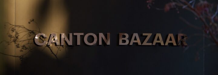 A dark background with the word Canton Bazaar in gold printed on it