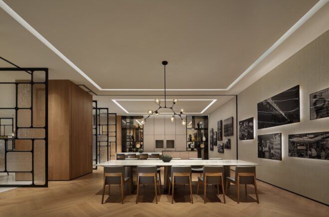 A long table with chairs tucked on either side of it and an artistic chandelier hanging above it