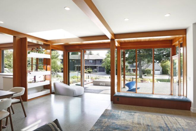 An open living room with wood accents that opens out onto the front yard.