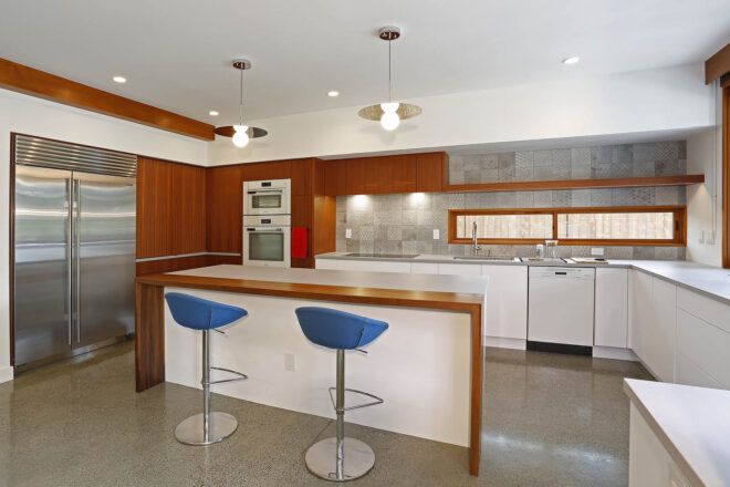 A kitchen with white counters and wood accents.