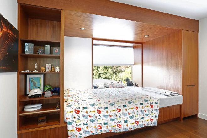 A child's bed built into a wooden shelving area.