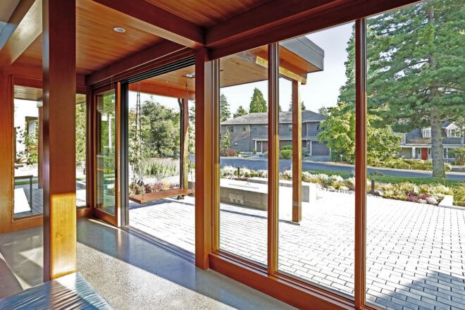 An open living room with wood accents that opens out onto the front yard.