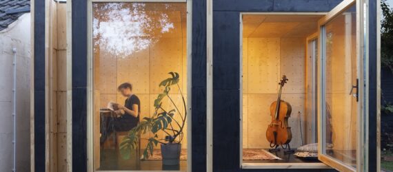 Glass windows with a person inside sitting on a chair with a cello beside them