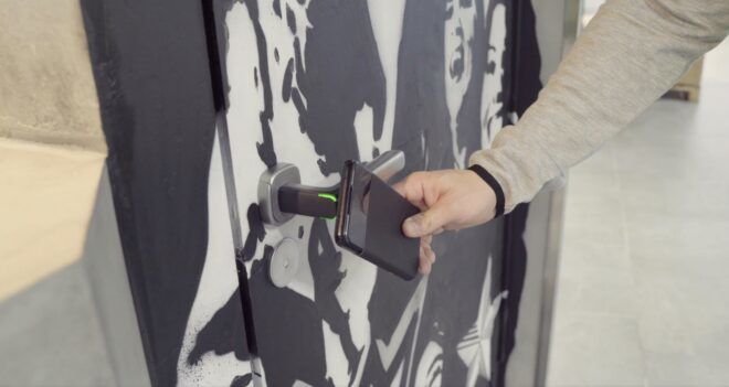 A hand placing a phone in front of a door handle