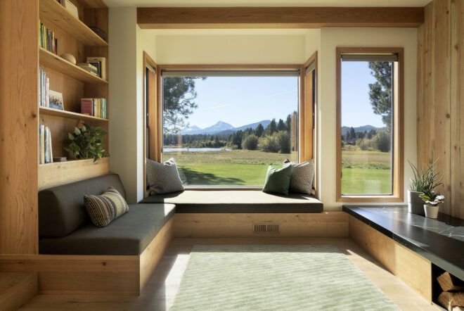 A living room with built-in seating surrounded by windows.