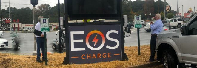 A sign that reads EOS Charge in a parking lot