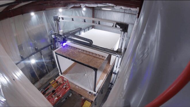 A machine working on a large rectangular shape of a 3D printed home