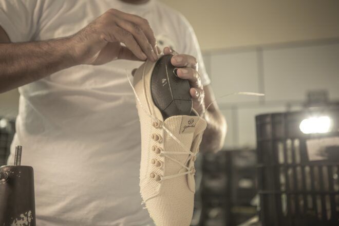 A hand holding a sneaker at a point on its tip
