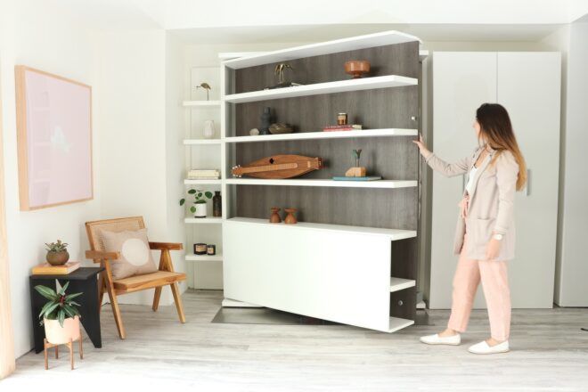 A woman touching a furniture that opens and is a movable wall