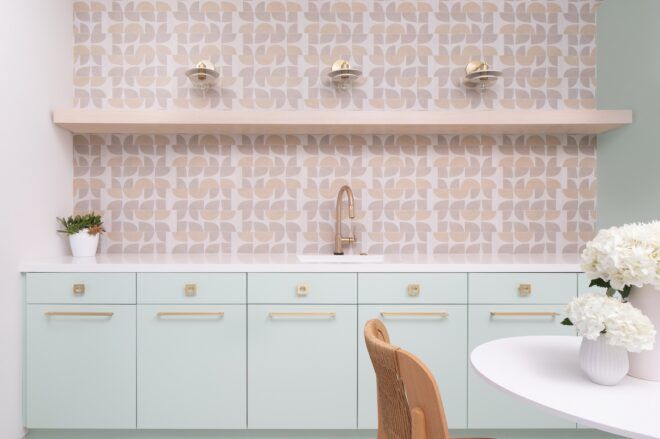 A countertop area with a light pink tiled backsplash and light blue cupboards underneath