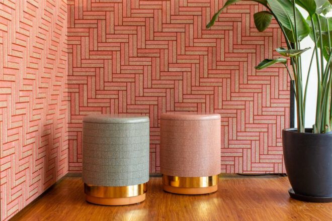 Two cylindrical tile-clad stools at the corner of a room with herringbone patterned wall tiles