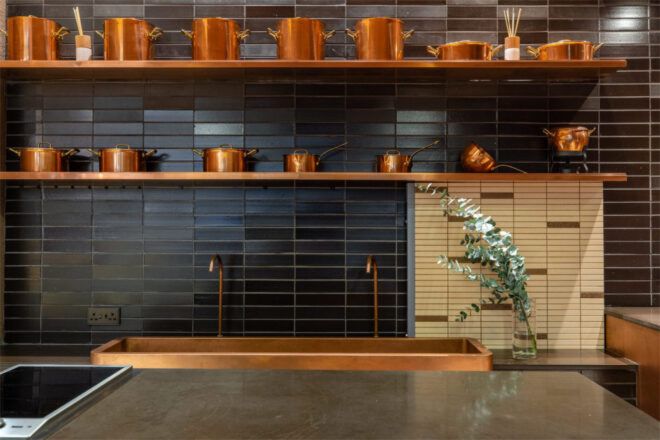 Kitchen counter with a dark backsplash and cream and brown tile detail on the right