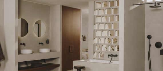 A white bathroom with an area to hang a bathrobe and a white bathtub