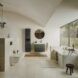 A minimalistic bathroom that has a white bathtub on the right that is against a window, a sink area with a circle mirror above it and another tiled area to the left