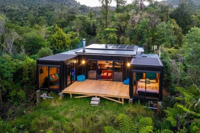 A one story house created with multiple shipping containers stacked together in a forest area