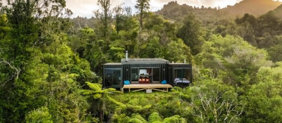 A house made of recycled shipping containers sits in a forest