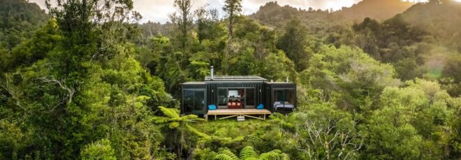 A house made of recycled shipping containers sits in a forest