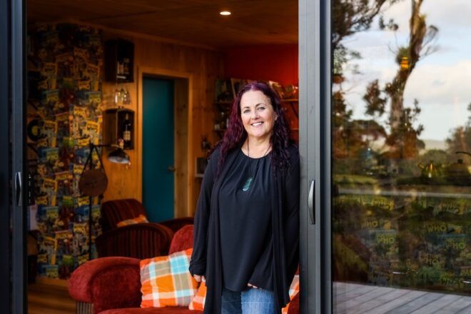 A woman with shoulder length brown hair leans against a glass sliding door frame