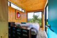 A bedroom with a floor-to-ceiling window at the foot of the bed