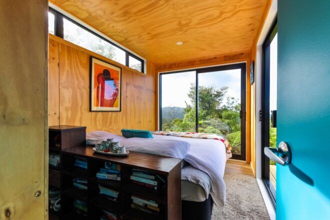 A bedroom with a floor-to-ceiling window at the foot of the bed