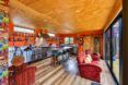 A couch is in front of a kitchen area with orange walls and wooden ceiling