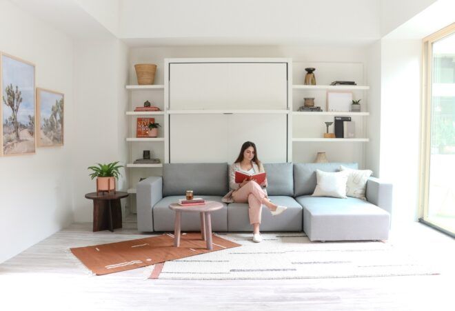 A woman sitting on a blue couch reading a red book
