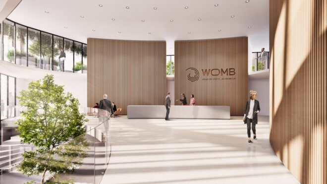 A main lobby area with a backdrop behind the front desk that reads WOMB