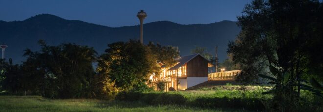 A home sit on a green hill lit up during the night time