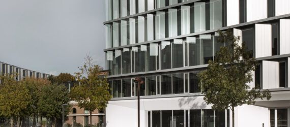 The exterior of a building with reflective, moveable shield-like structures.