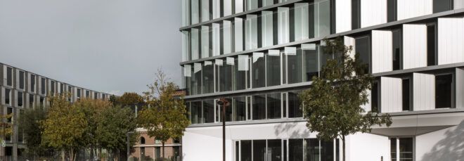 The exterior of a building with reflective, moveable shield-like structures.