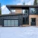 A two story house with a garage in a snowy area