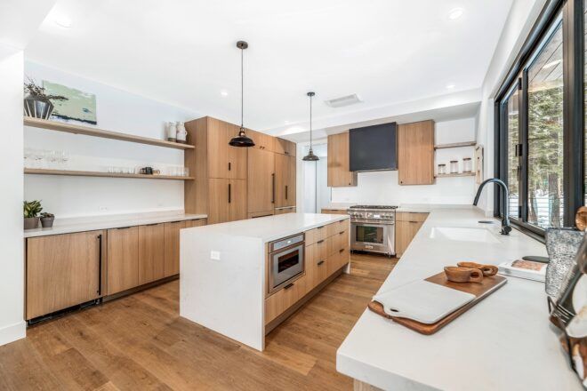 A kitchen room with a large rectangle island and brown cupboards accented against the white walls