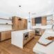 A kitchen room with a large rectangle island and brown cupboards accented against the white walls