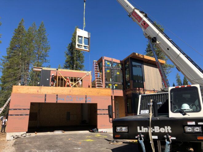 A machine lifting parts of the house to assemble the house
