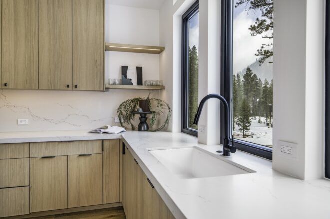 A sink area with white countertops and a view out to the mountains