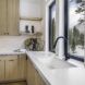 A sink area with white countertops and a view out to the mountains