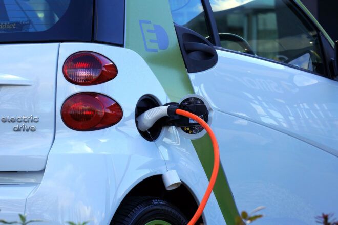 The back of a white electric car being charged.