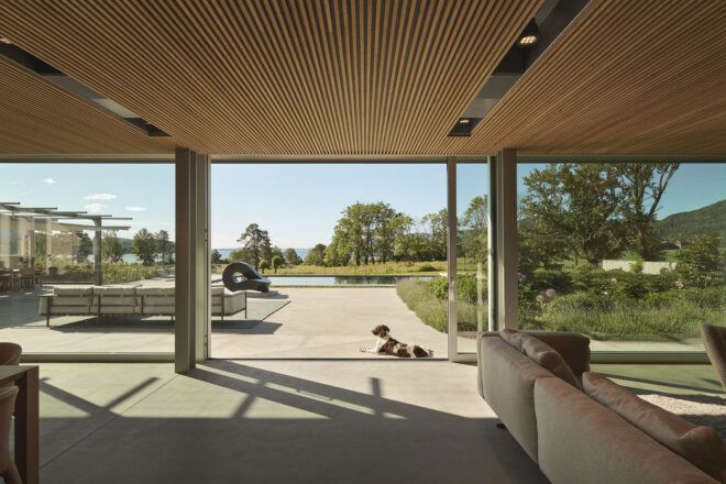 A living room open to a deck area where a dog lays down.