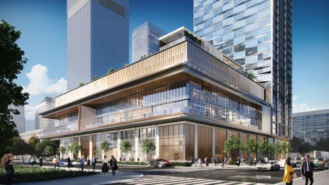 A square building full of glass windows sits at an intersection in the city