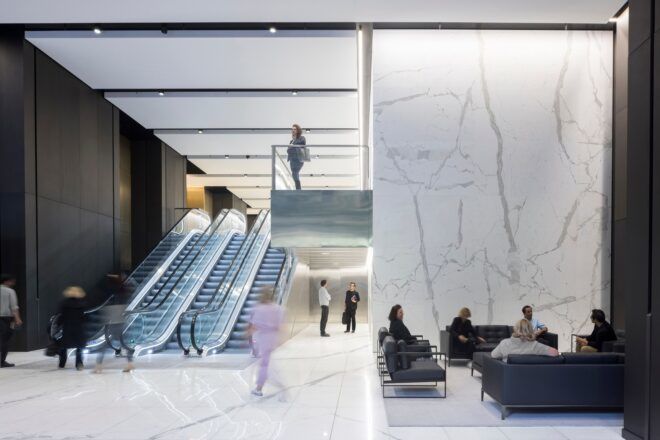 The white lobby has a seating area and escalators leading up to the second floor