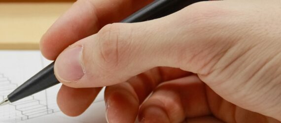 A hand holding a black pen