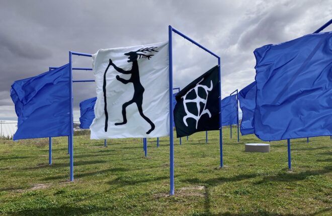 A white and black flag stand side-by-side to each other amidst a sea of blue flags