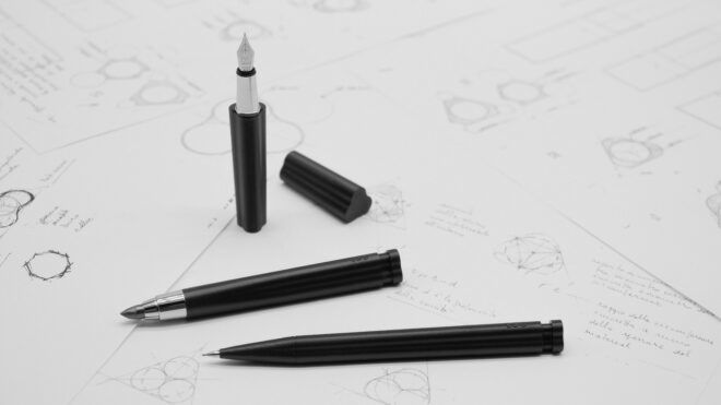 A fountain pen with two other writing utensils on a white paper filled with sketches