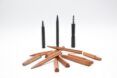 Three different pens in front of a pile of wooden prototypes