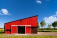 A red barn with a slanted roof has its doors open