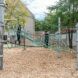 Two kids playing on a jungle gym in a playground that has ropes suspended above the ground